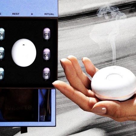 A hand holding the Lunette sleep aid device next to a package of the Lunette withe scnet pods