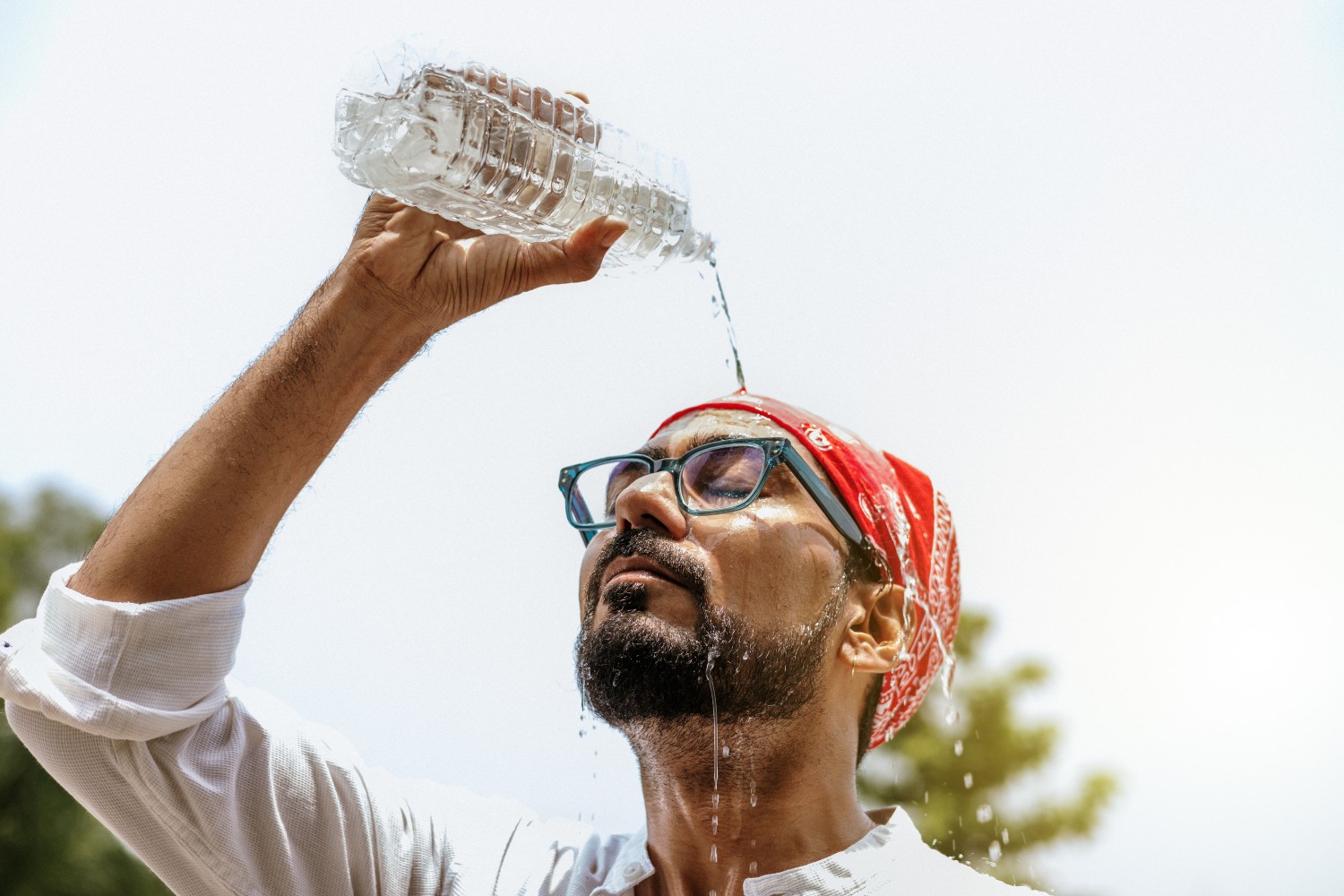 Man pouring water on his face to cool off
