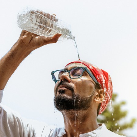 Man pouring water on his face to cool off