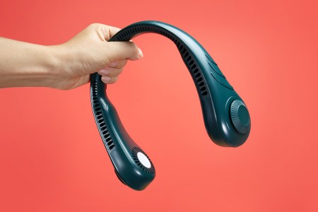 A hand holding a neck fan in front of a red-orange background