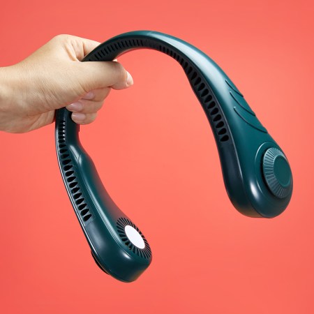 A hand holding a neck fan in front of a red-orange background