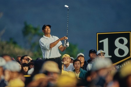 Fans surround Tiger Woods as he holds his golf swing pose.