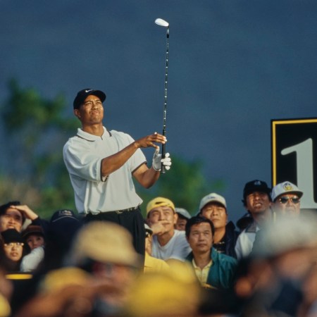Fans surround Tiger Woods as he holds his golf swing pose.