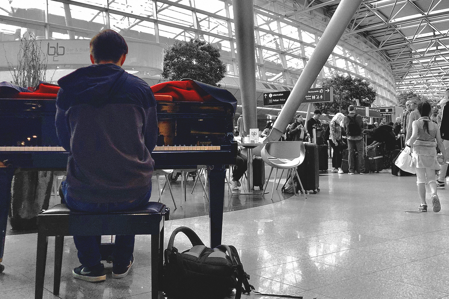 Airport musician in color against a B&W background of the airport