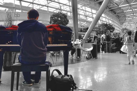 Airport musician in color against a B&W background of the airport