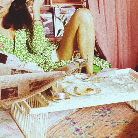 A woman in bed with a tray that includes a glass of wine