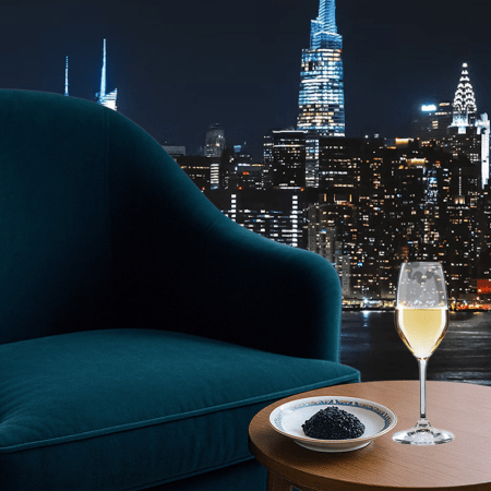 a glass of champagne on a table next to a plush chair overlooking a city skyline