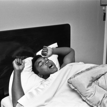 Muhammad Ali in bed yawning, black and white photo.