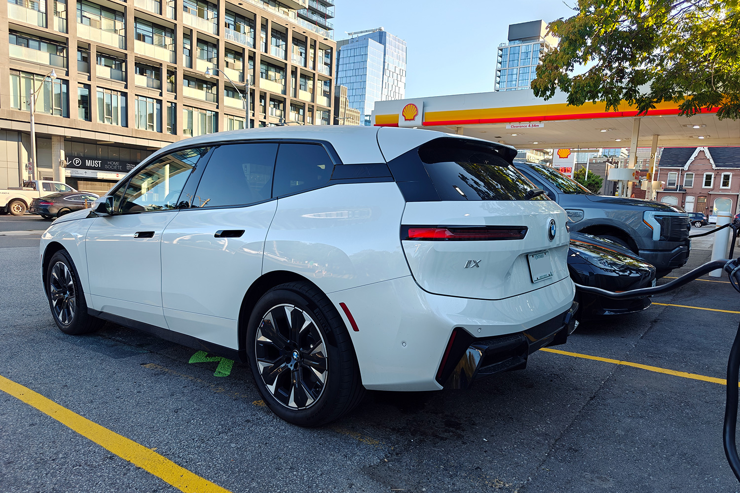 Three EVs sitting at a charging station, including a BMW, Tesla and Ford