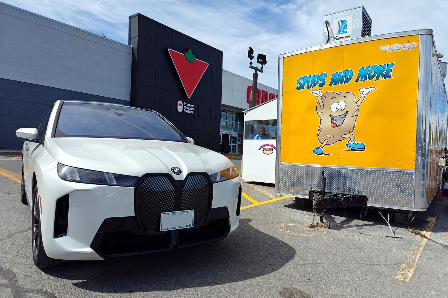 An electric BMW SUV outside a Canadian Tire store and sitting next to a food truck during a road trip