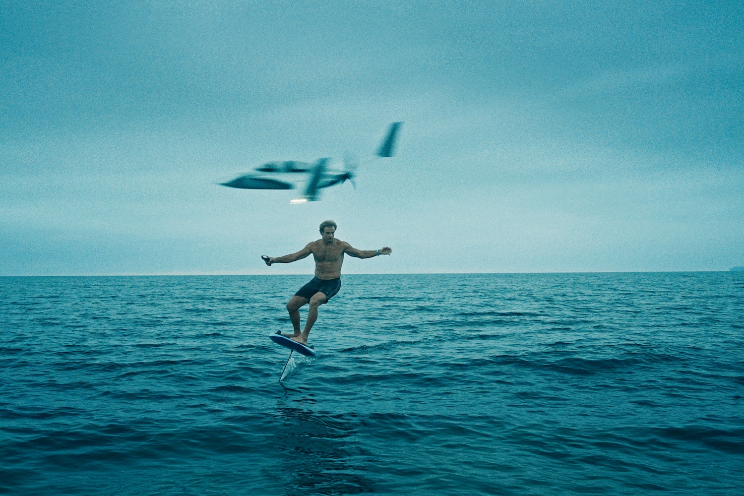 A still from Laird Hamilton's documentary "Dawn Ready" — he's on a hydrofoil with a plane behind him.