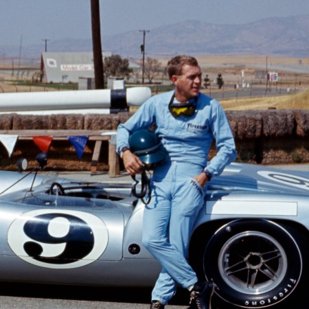 Steve McQueen with a racing car behind him