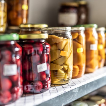 Homemade fruit and vegetable preserves in glass jars on a shelf in the pantry