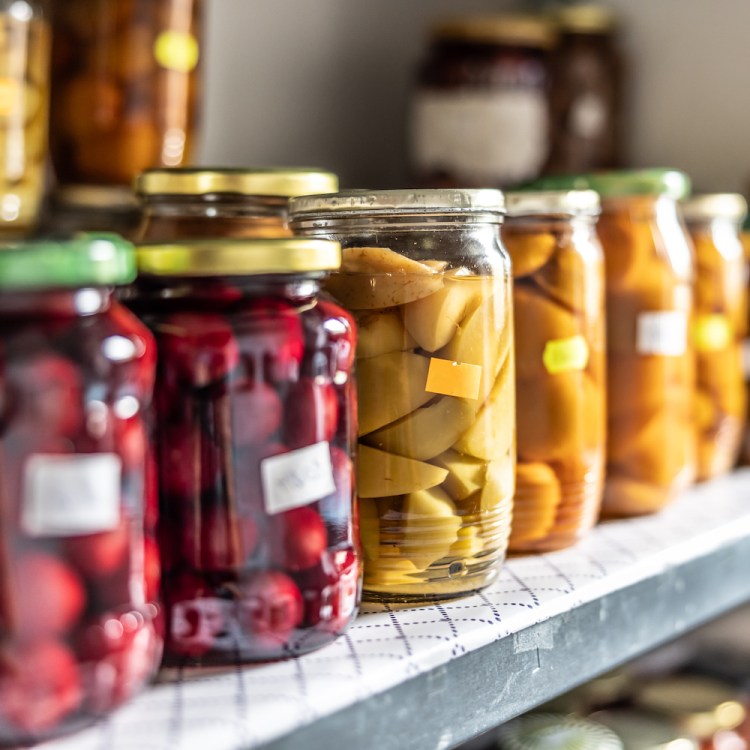 Homemade fruit and vegetable preserves in glass jars on a shelf in the pantry