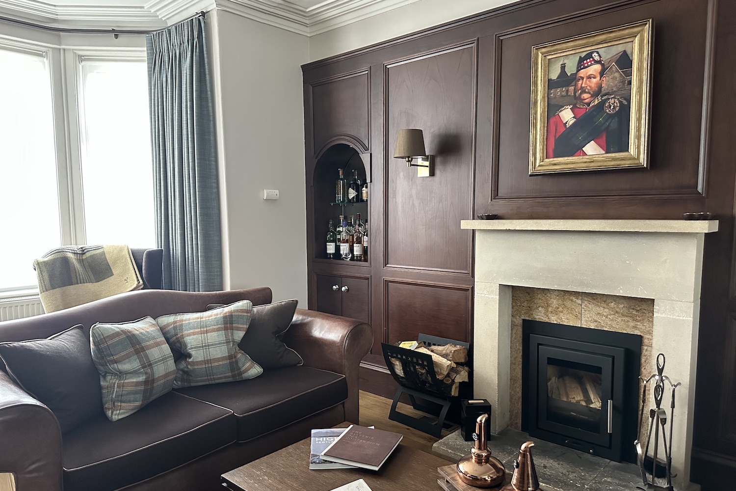 a cottage living room with a wood-burning fireplace, dark wood and bay window