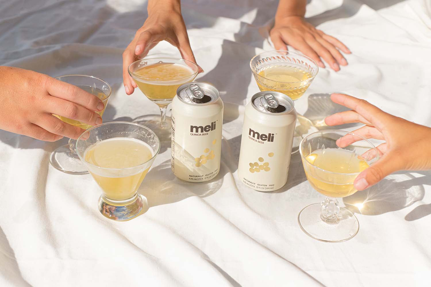 Two cans and four glasses of meli beer on a table