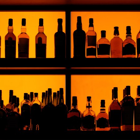 Bottles sitting on shelf in a bar, back lit