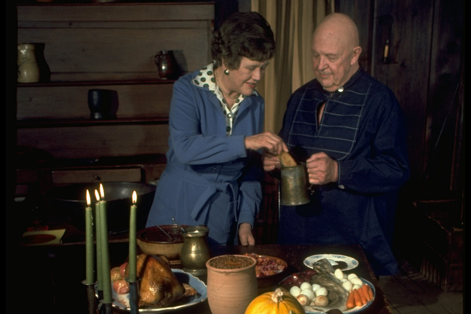Julia Child and James Beard standing behind a table arrayed w. autumnal foods while appearing on TV show Revolutionary Recipes