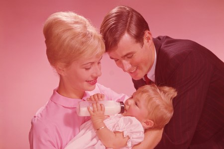 Parents watching baby girl (12-15 months) drinking from bottle