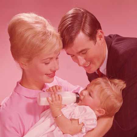 Parents watching baby girl (12-15 months) drinking from bottle