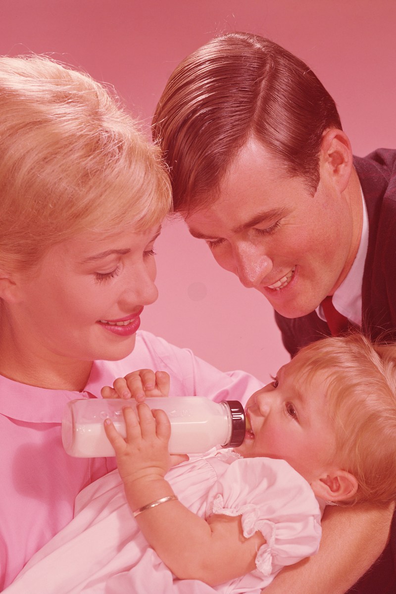 Parents watching baby girl (12-15 months) drinking from bottle
