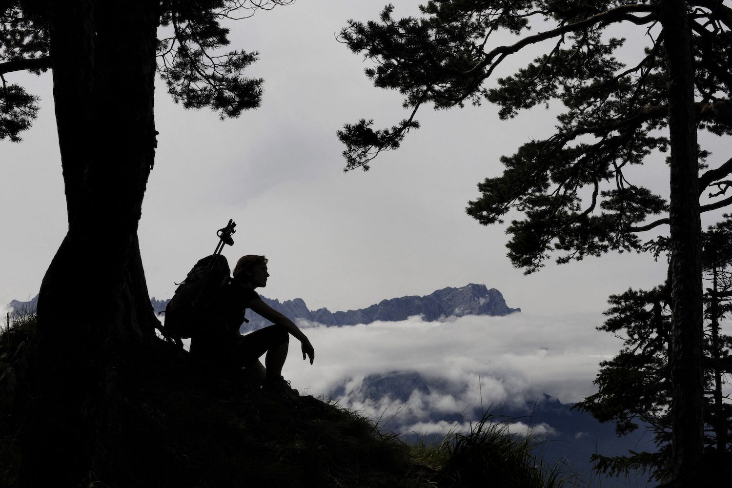 A hiker sitting against a tree.