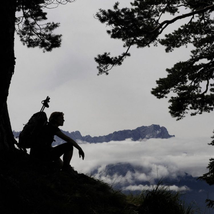 A hiker sitting against a tree.