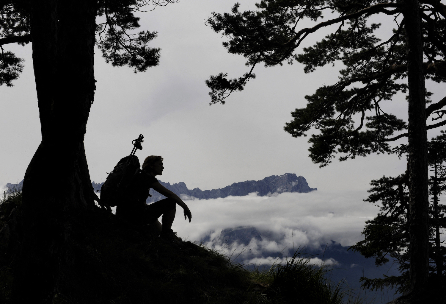 A hiker sitting against a tree.