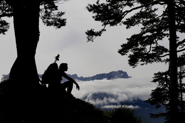 A hiker sitting against a tree.