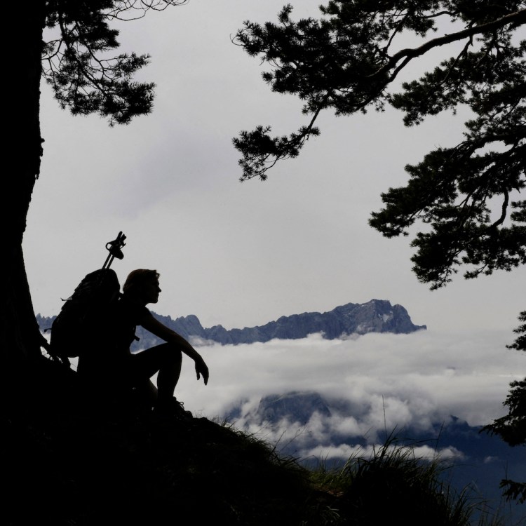 A hiker sitting against a tree.