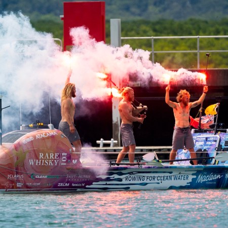The three Maclean brothers Jamie, Ewan and Lachlan in an ocean rowboat, lighting celebratory flares.