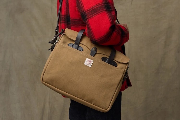 a man wearing a red flannel and holding a tan Filson briefcase