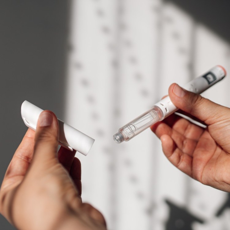 Hands holding a GLP-1 injector