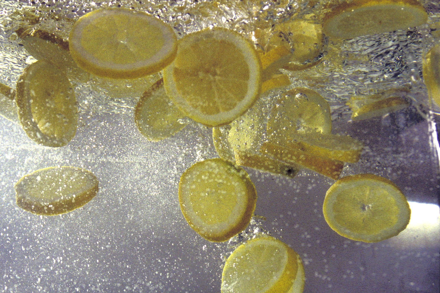 Lemon slices splashed into a pitcher of water.