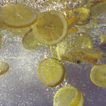Lemon slices splashed into a pitcher of water.