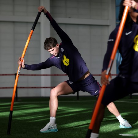 Some soccer players stretching with a weighted stick.