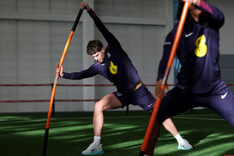 Some soccer players stretching with a weighted stick.