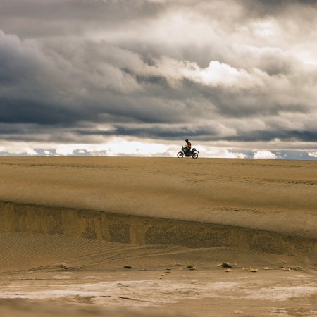 A man on a motorcycle in sand.