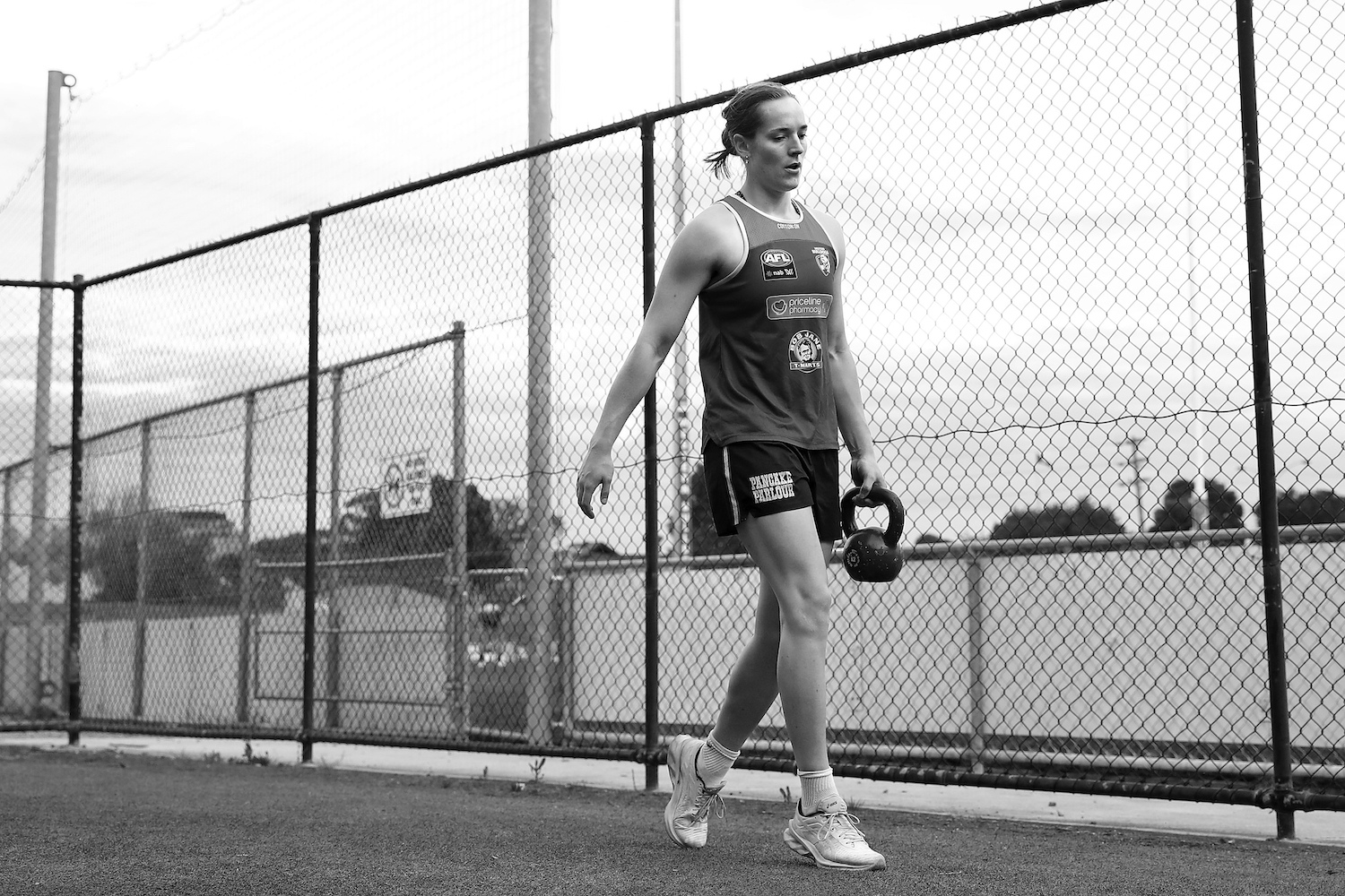 A woman carrying a kettlebell in the style of a suitcase carry.
