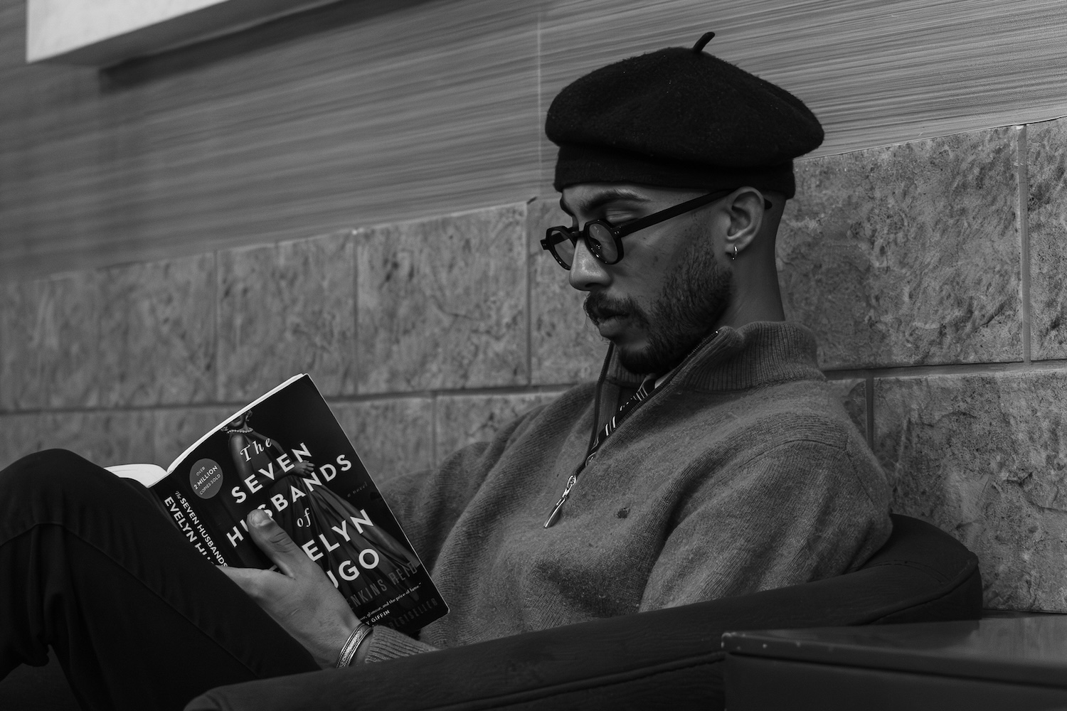 A man reading a book and wearing a quarter zip