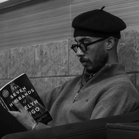 A man reading a book and wearing a quarter zip