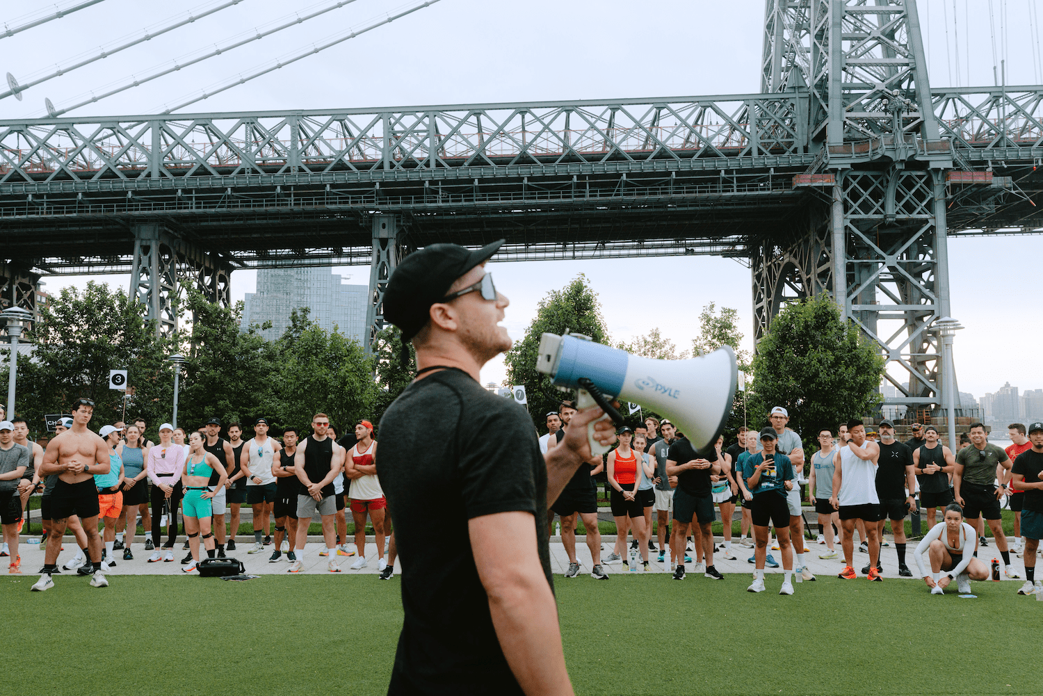 A man speaks into a bullhorn as competitors gather at the start line.