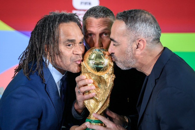 Soccer players kissing the World Cup trophy