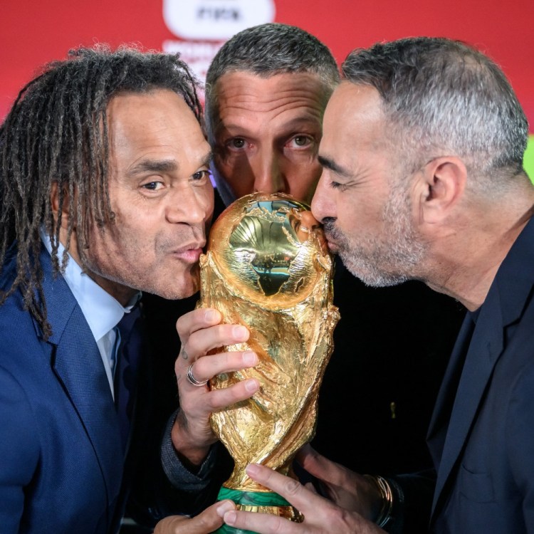 Soccer players kissing the World Cup trophy