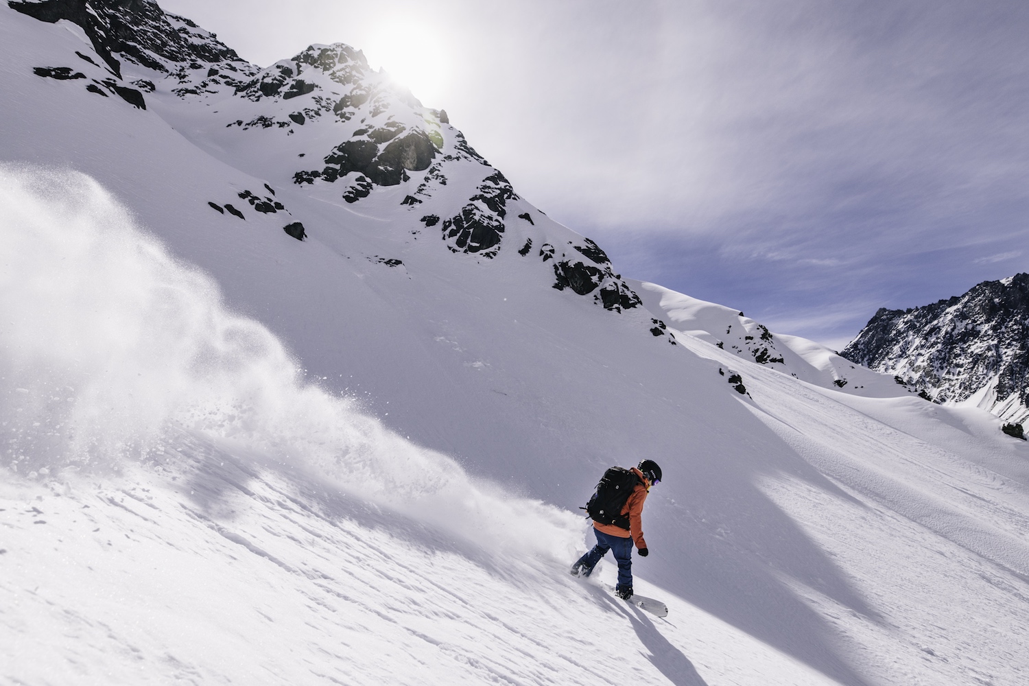 Sun breaks through the clouds as a skier makes their way down the mountain.
