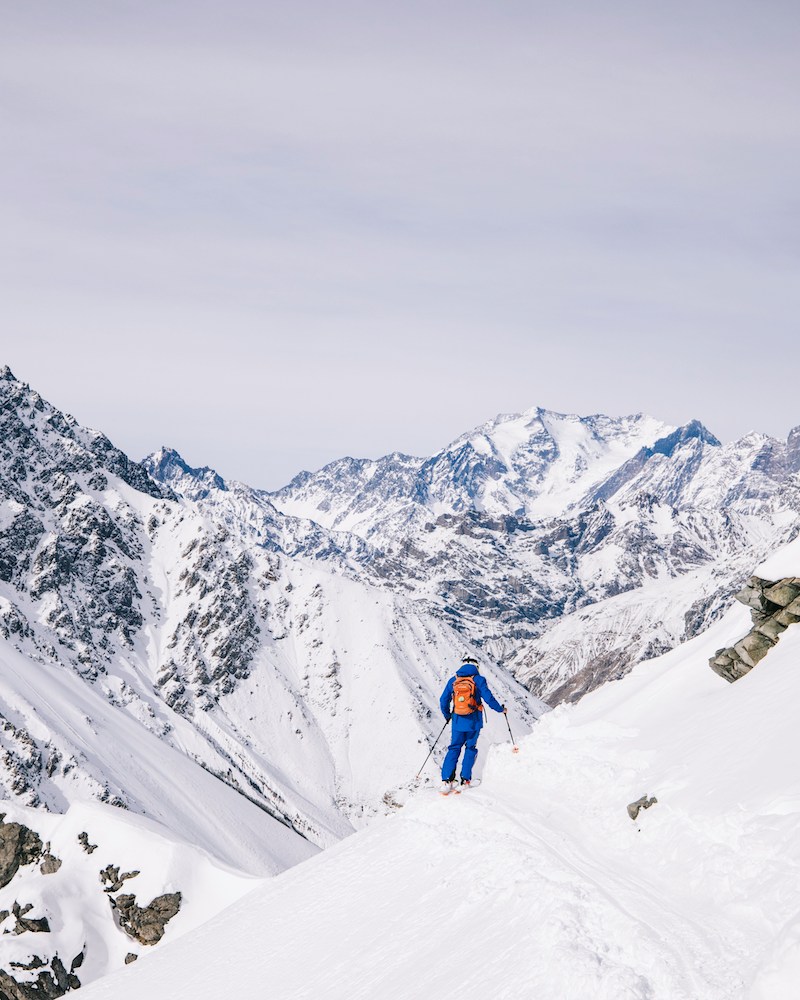 A skier on a narrow path with the Andes mountains in the background at Portillo, the legendary ski resort in Chile