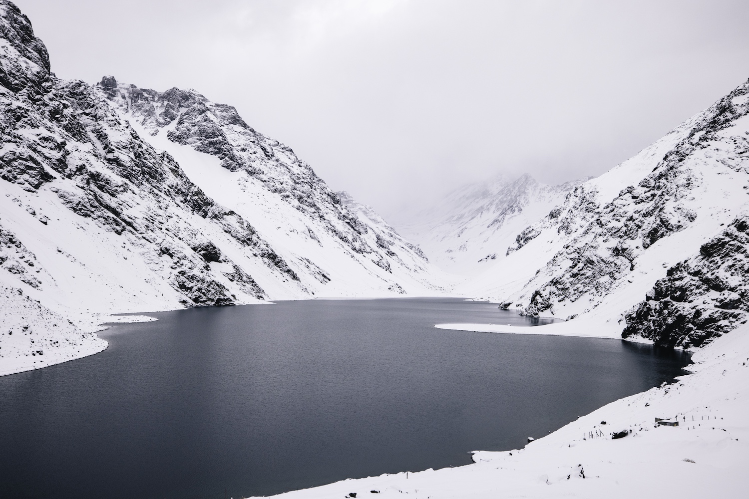 A deep blue lake surrounded by snowy mountains.