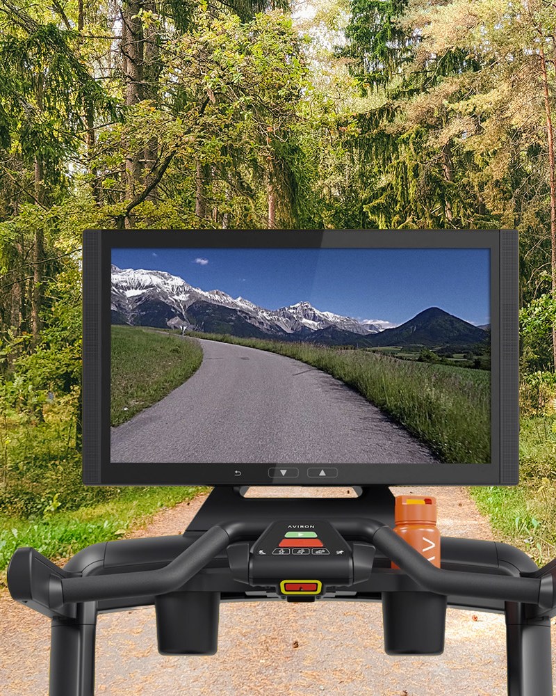A treadmill screen from the Aviron Victory Treadmill Plus superimposed on a woodland trail.