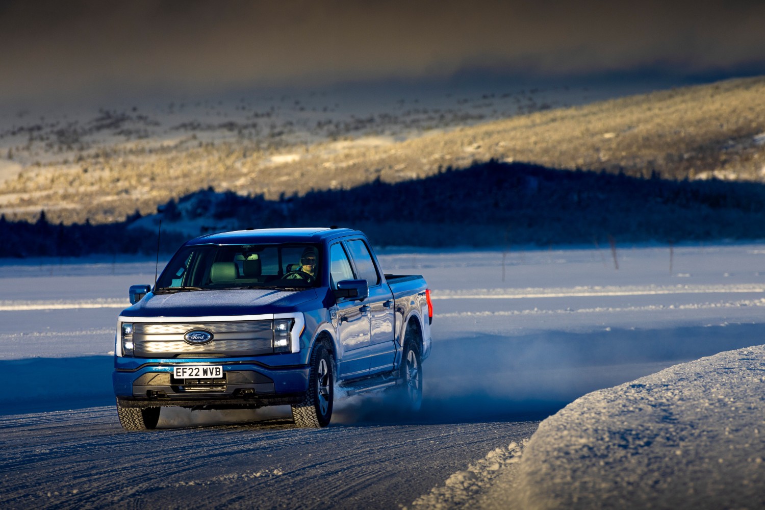 The all-electric Ford F-150 Lightning truck driving on an icy, snowy road