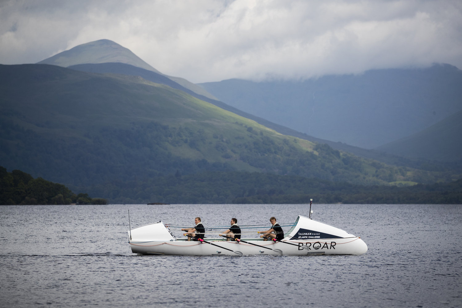 Three rowers in a boat on Loch Lomond.